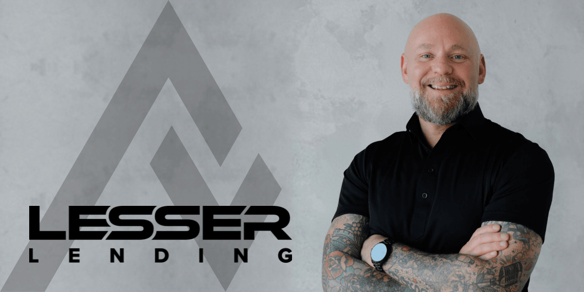 Smiling man with tattoos wearing a black polo shirt next to company logo