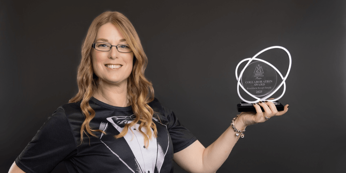 Woman in a tuxedo shirt holds an award in front of a dark background