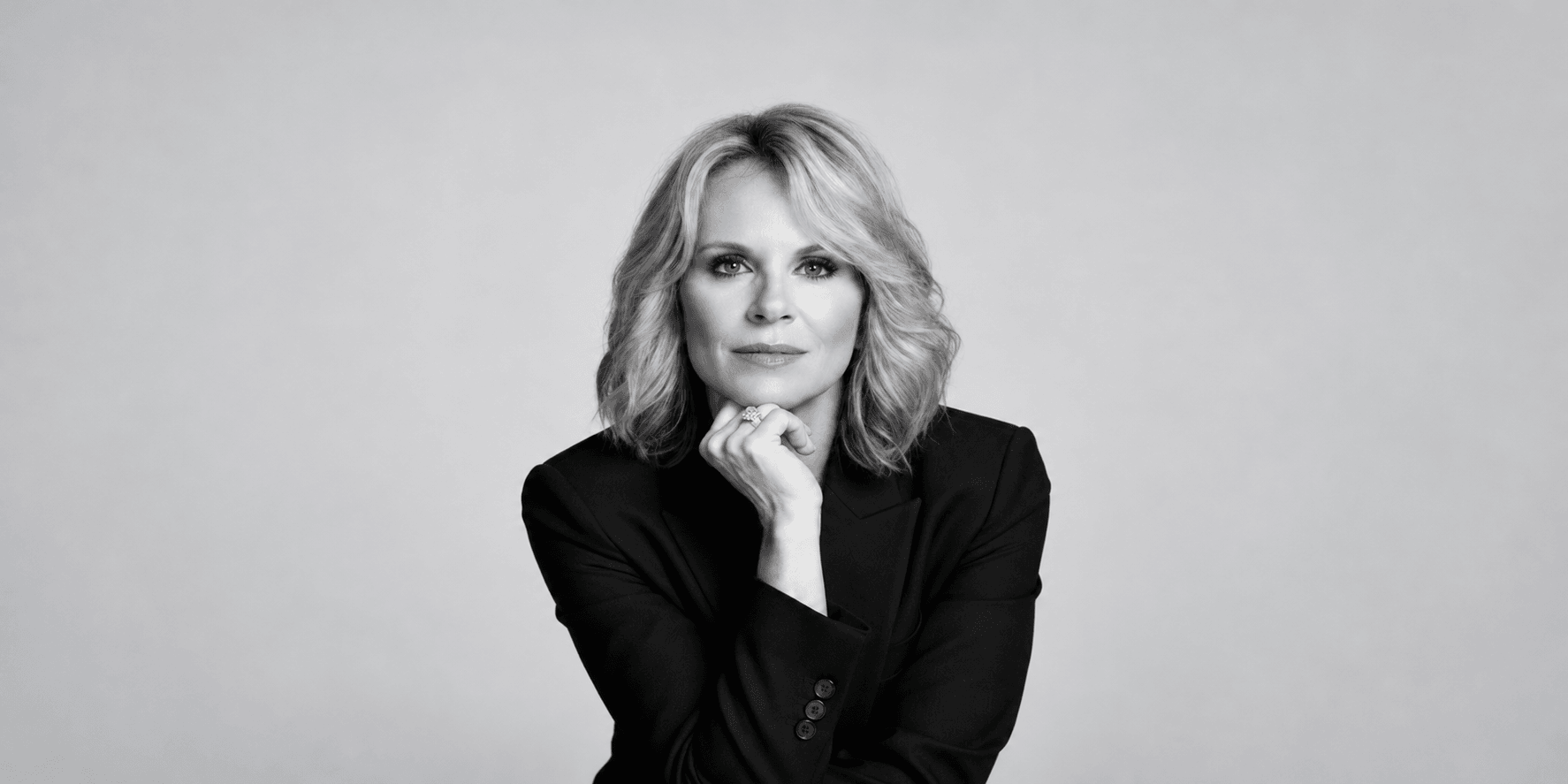 Black and white portrait of a woman in a blazer, resting her chin on hand