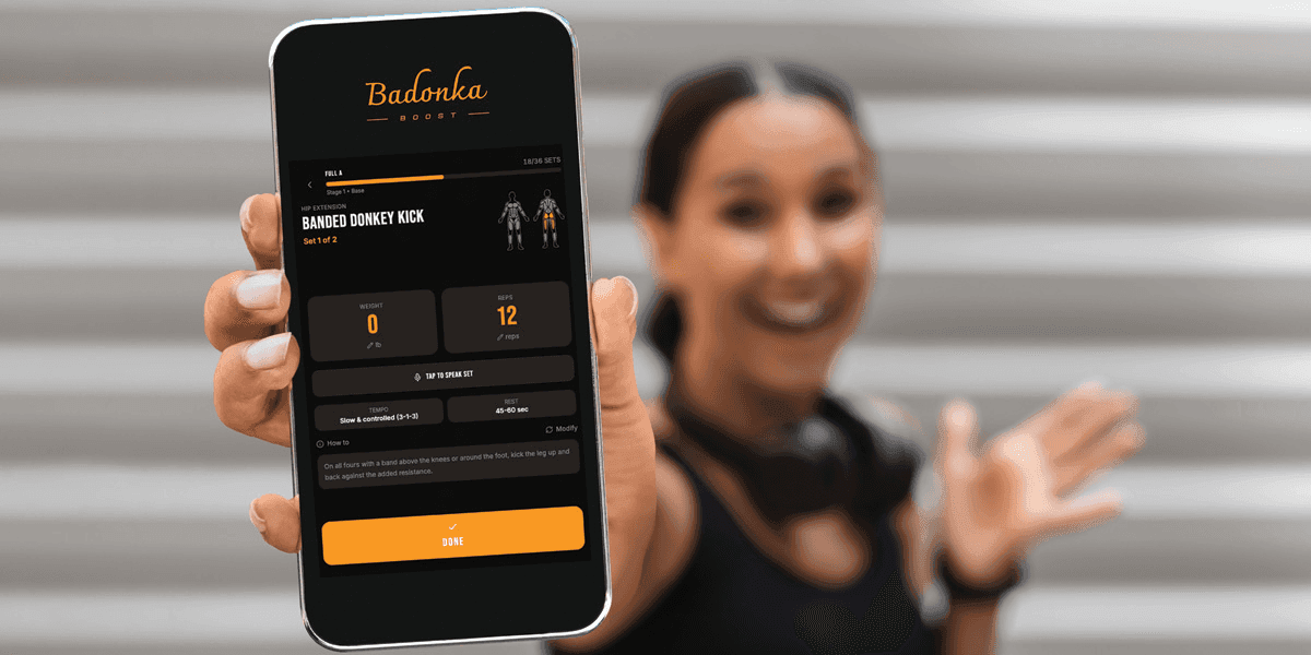 Person holding smartphone displaying the Badonka Boost fitness app workout screen with guided exercise tracking.