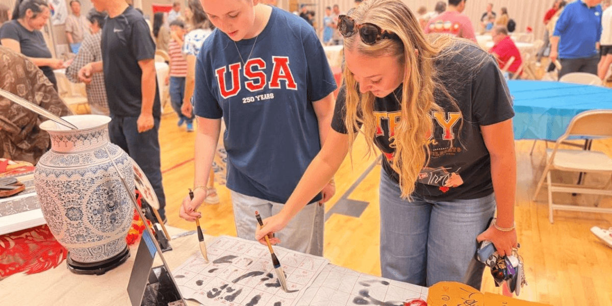 Two women engaged in an activity at a community event, examining artwork together