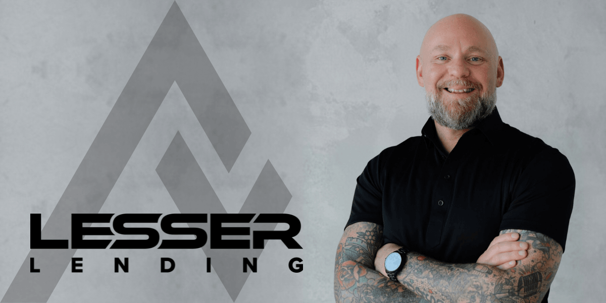 Smiling man with tattoos wearing a black polo shirt next to company logo