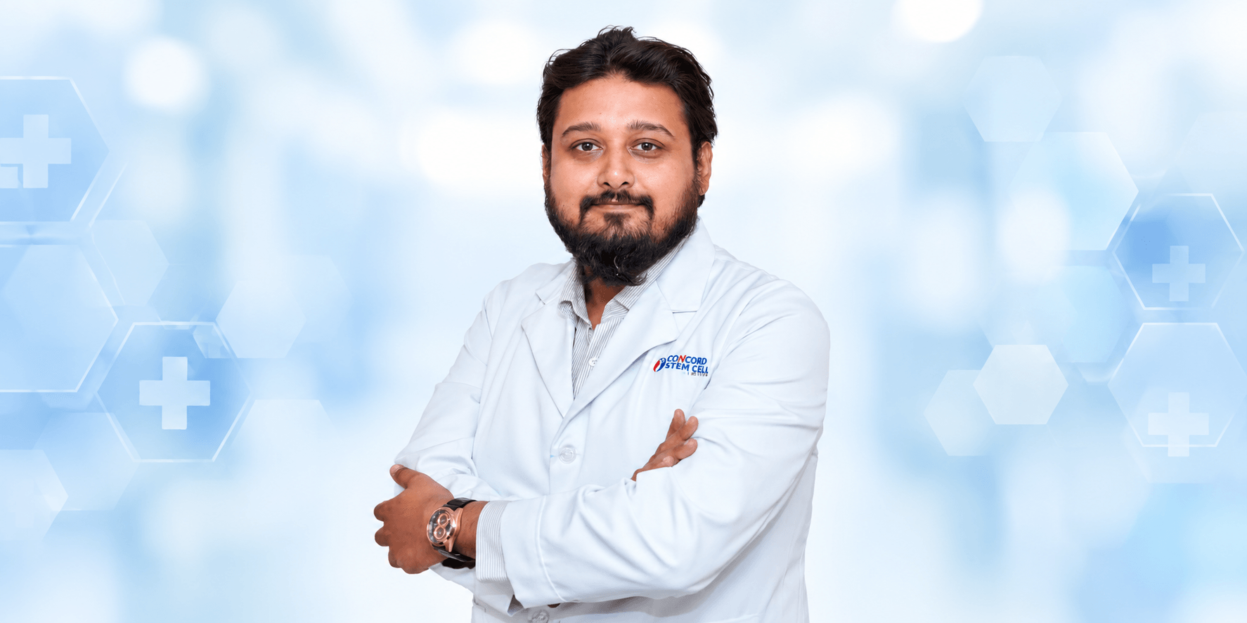A man in a white lab coat poses confidently against a medical background