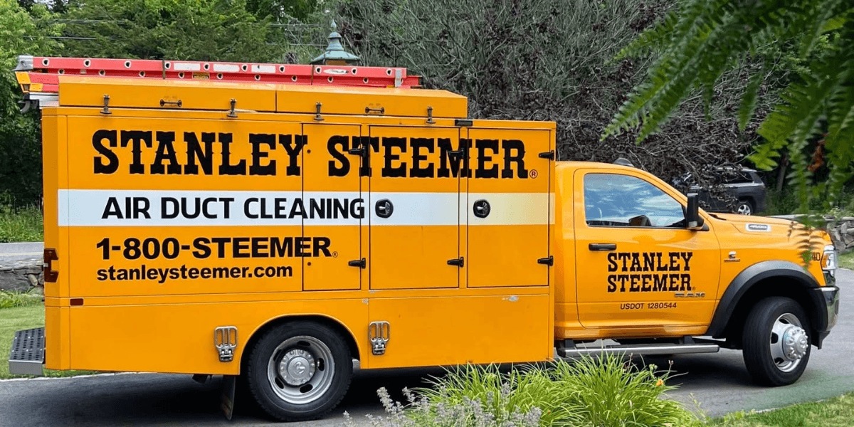 Bright yellow Stanley Steemer truck promoting air duct cleaning services parked on the street