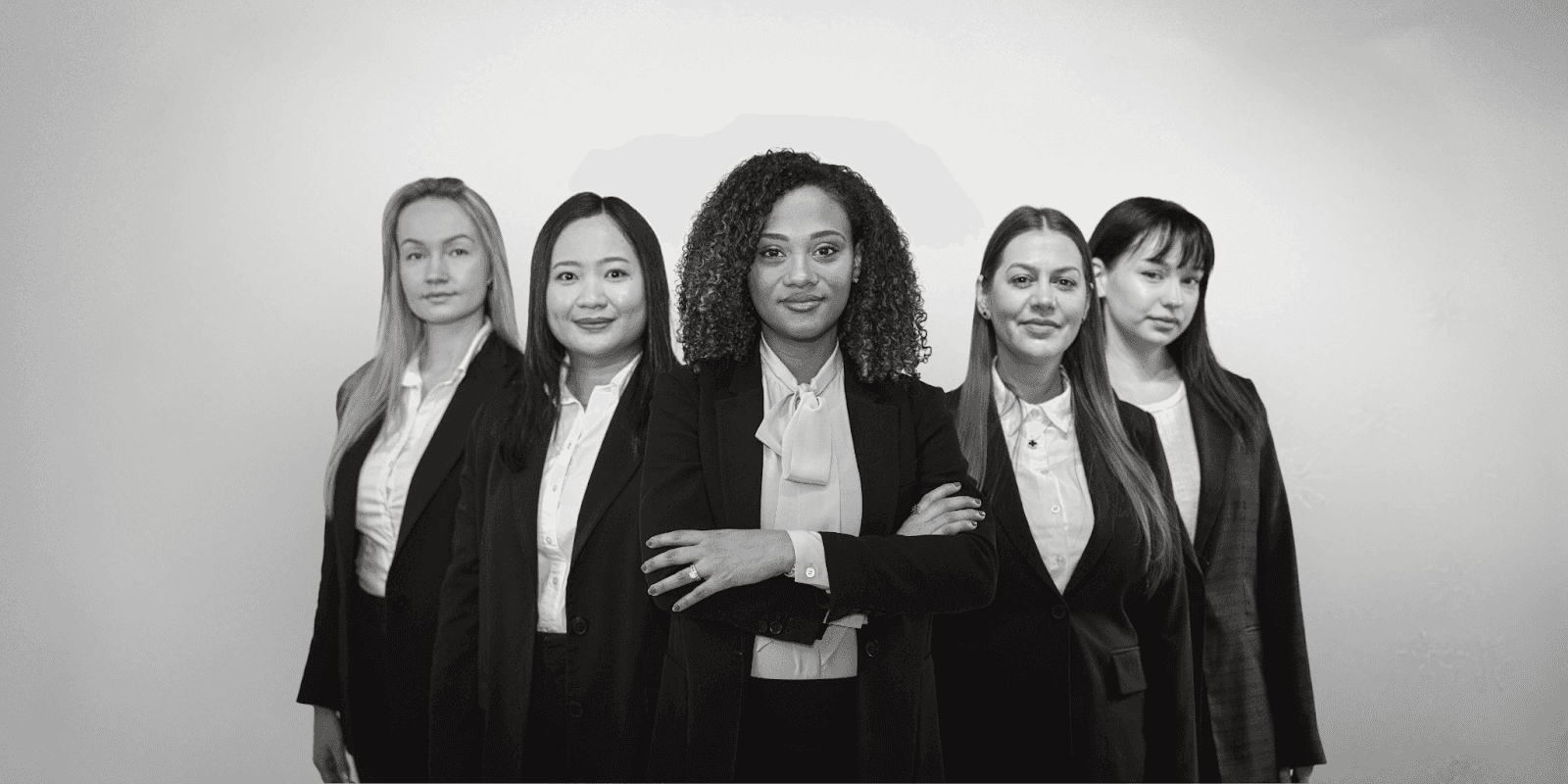 Five professional women in business attire, with Gloria Domingos centered, representing Domingos Law Firm’s leadership and diversity.