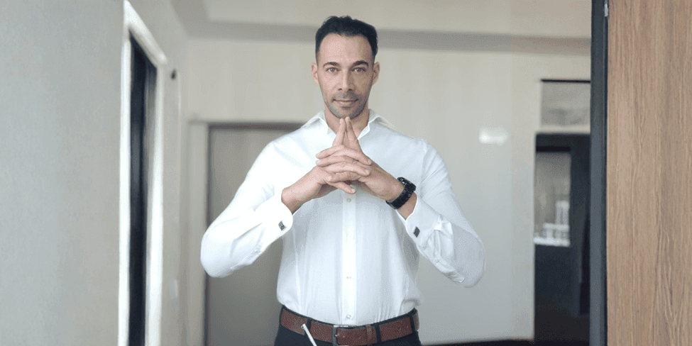 Simone Giaquinto, in a white shirt, gestures while discussing his coaching book "CODE OF WAR" and its transformative insights.