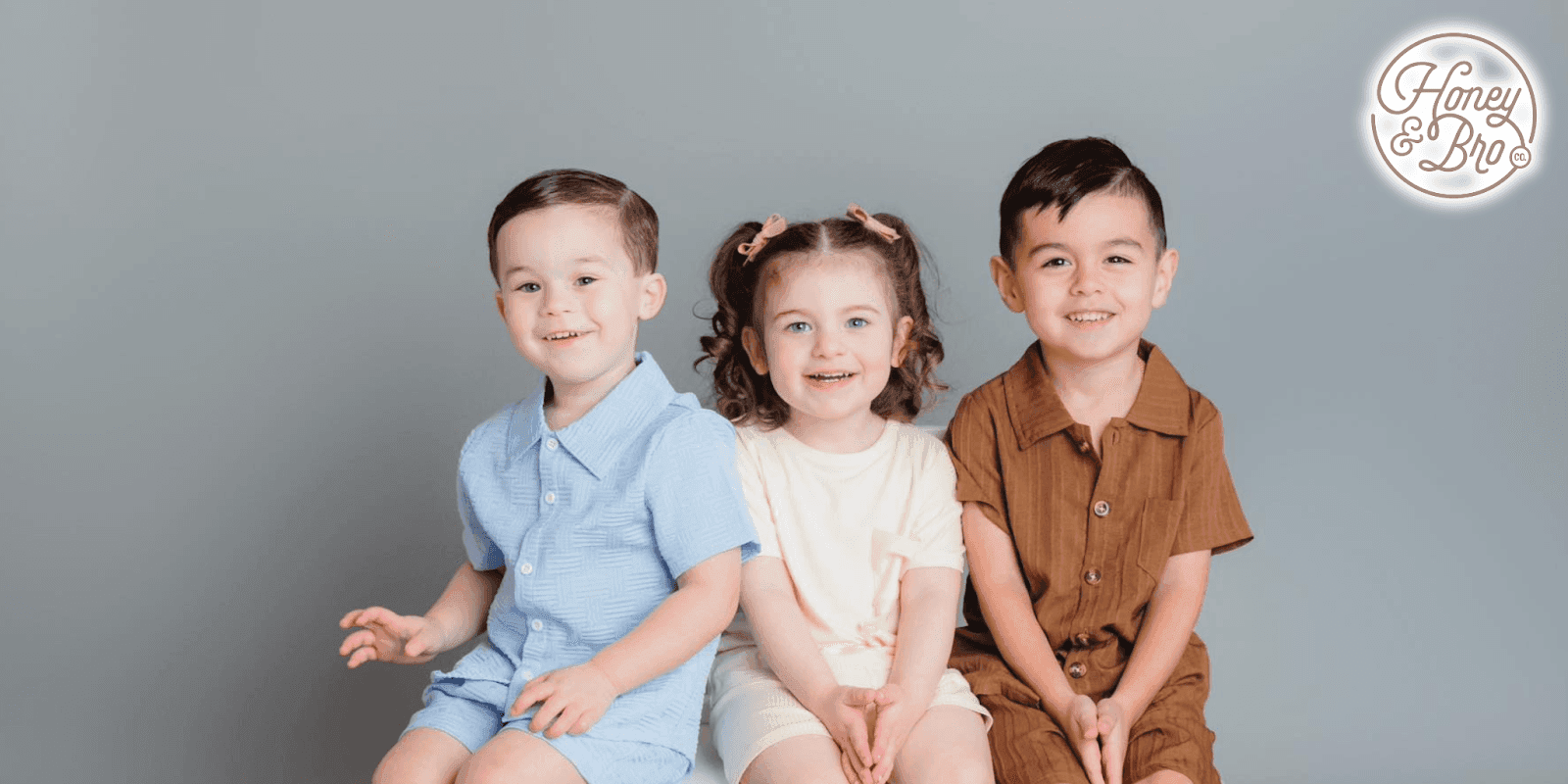 Three kids wearing comfortable, eco-friendly clothing from The Honey and Bro Co., showcasing playful and practical designs.