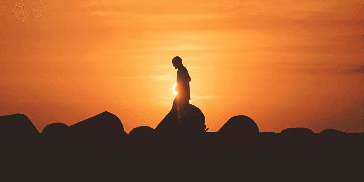 Silhouette of a lone figure walking over rocks at sunset, symbolizing Craig Logsdon’s transformative journey.
