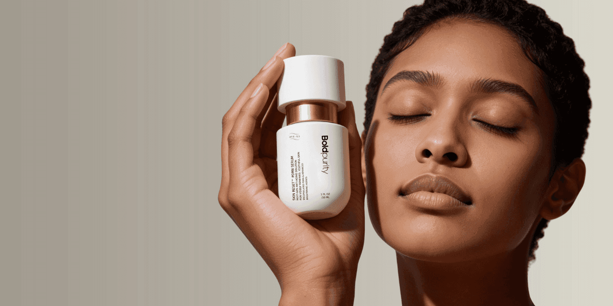 A person holding a skincare product from BoldPurity, with eyes closed, symbolizing a focused, science-driven approach to skincare.