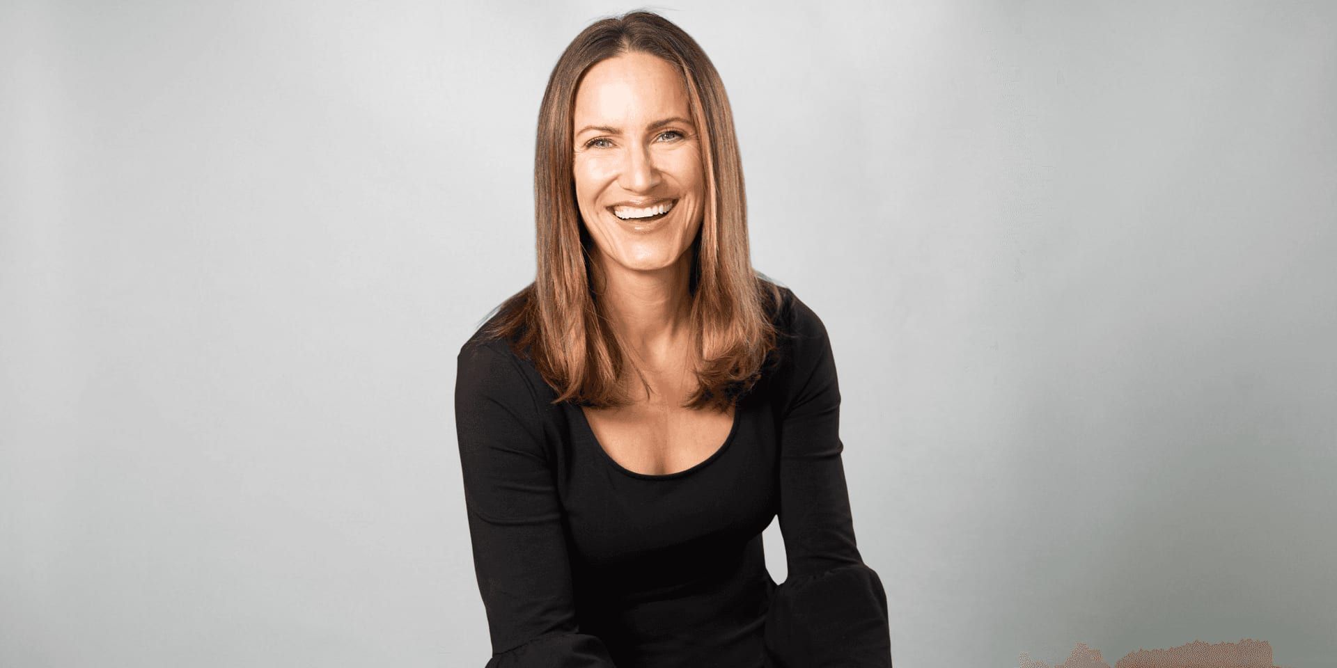 Michelle Schurer wearing a black top against a light gray studio background.