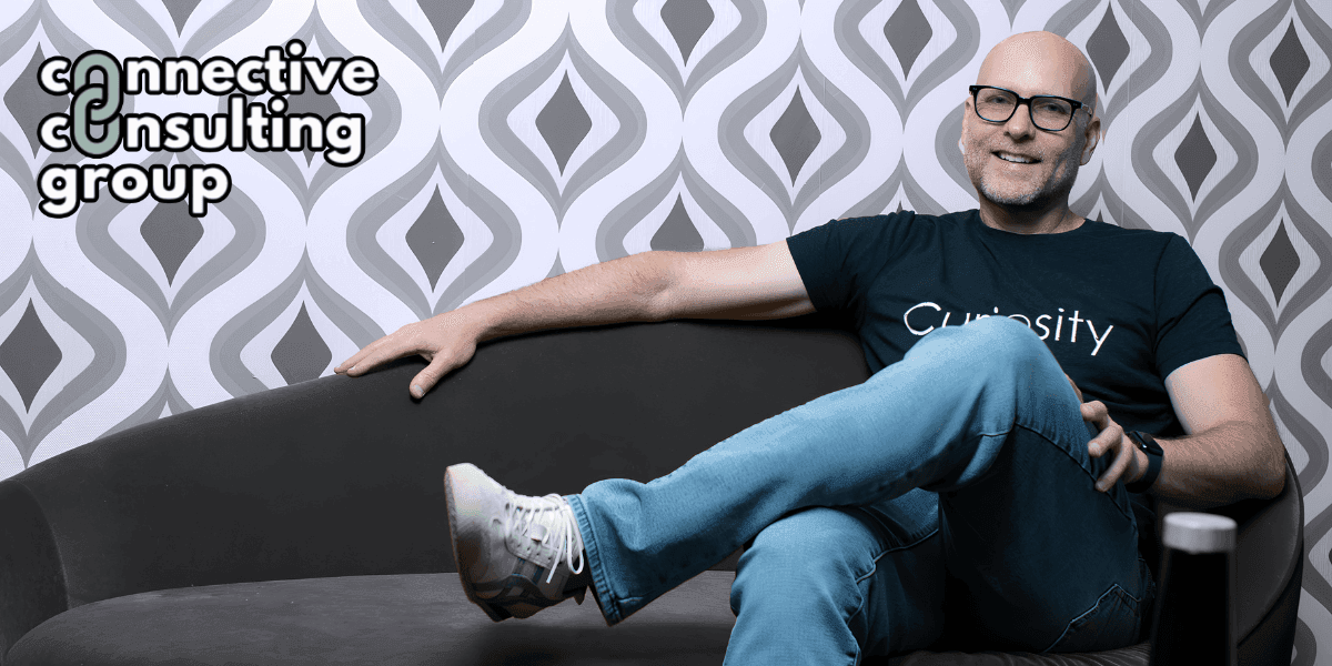Ryan Ware, founder of Connective Consulting Group, seated on a couch, promoting curiosity-driven leadership and organizational changeability in construction.