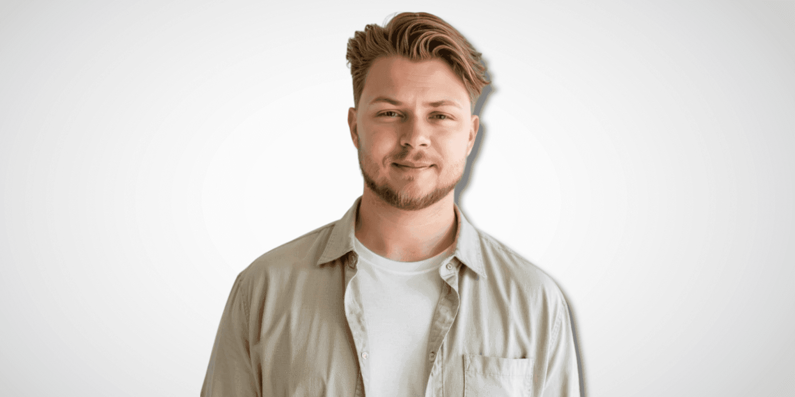 Portrait of a smiling man with short hair and a beard, wearing a light beige shirt over a white T-shirt, with a neutral background