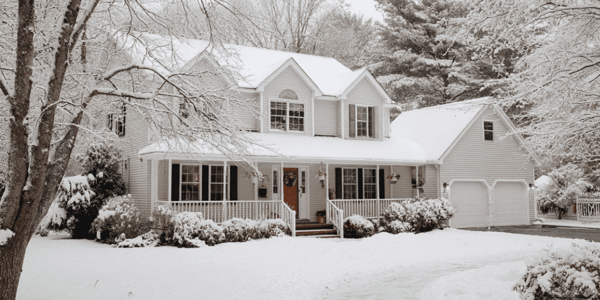 Snow-covered suburban home showcasing winter conditions, highlighting need for roof inspection and preparation in Manchester, NH.