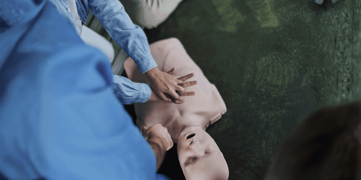 Close-up of hands performing CPR on a mannequin, demonstrating Basic Life Support (BLS) training in a healthcare setting