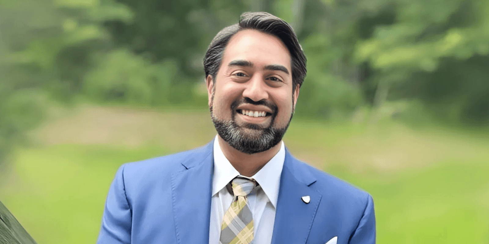 Man in blue suit smiling outdoors, representing HP Attorneys' founder Hiten H. Patel.