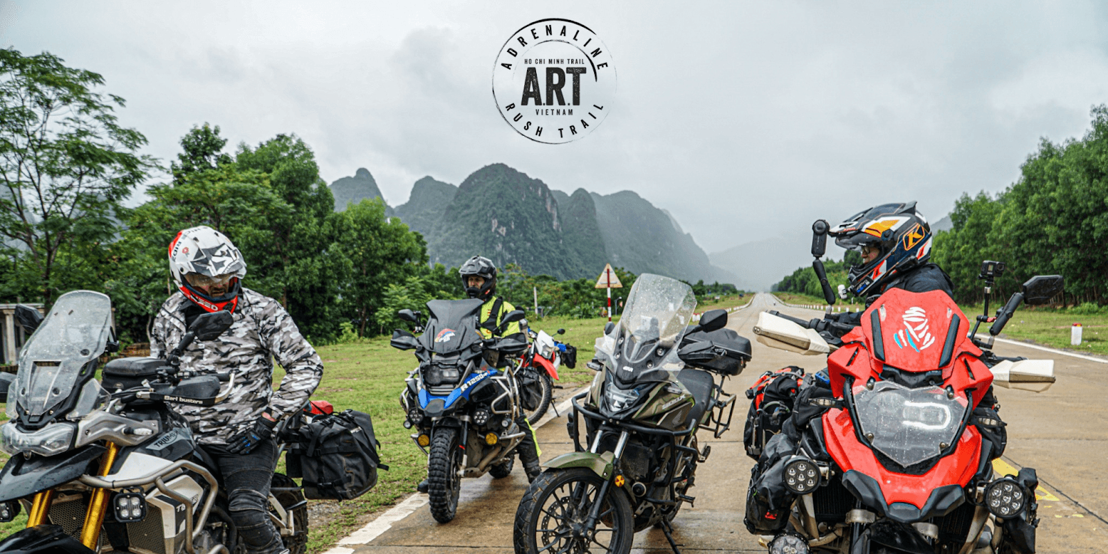 Riders on adventure motorcycles pause along Vietnam's Ho Chi Minh Trail, surrounded by stunning mountainous landscapes with ART branding.