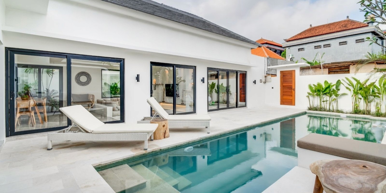 Modern Bali villa with private pool, lounge chairs, and open glass doors reflecting a clean, structured construction approach.