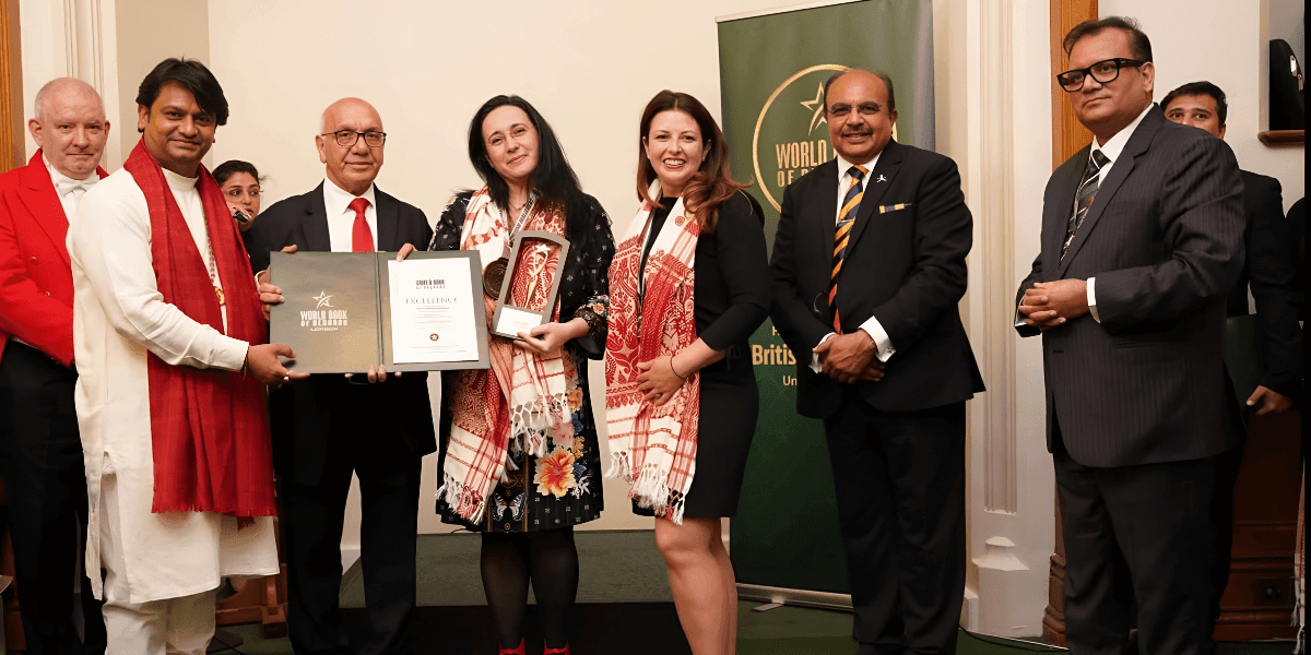 Group of award recipients and presenters at World Book of Records ceremony in London, holding certificates and trophies.