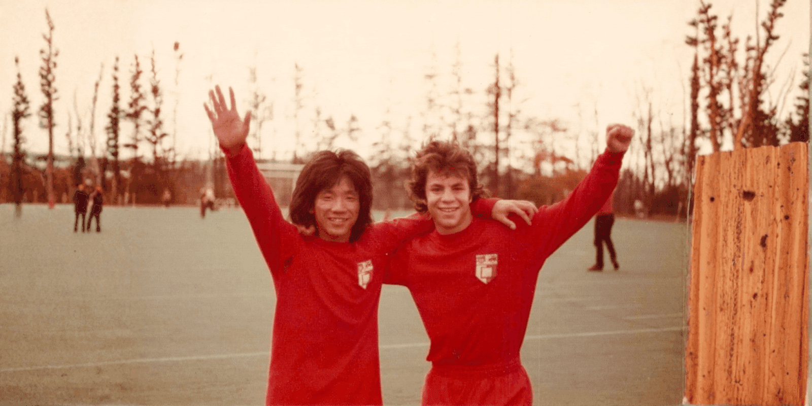 Joe Mui and teammate at soccer field, celebrating a moment of triumph.