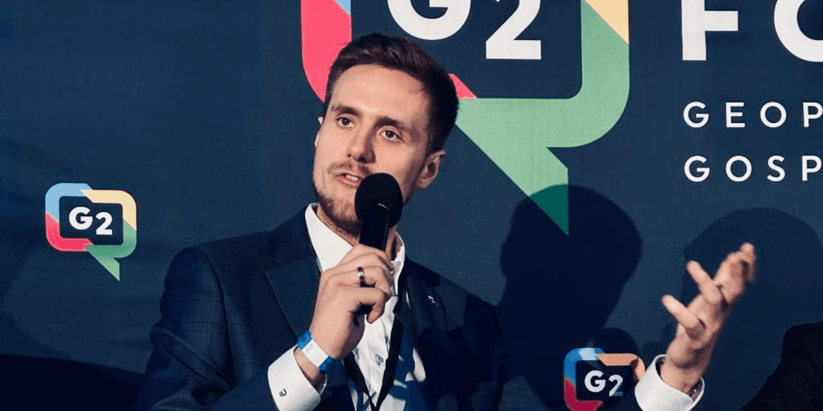 Łukasz Bugajski speaking at a G2 forum, emphasizing intelligence-driven security solutions for high-risk environments and strategic action.
