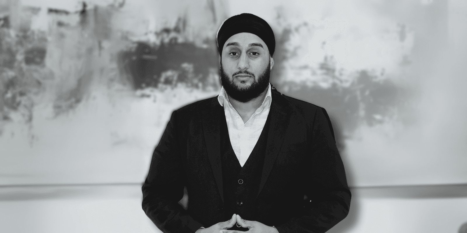 Eknoor Singh Bains, CEO of Limitless Financial, standing confidently in a suit against a blurred abstract background.
