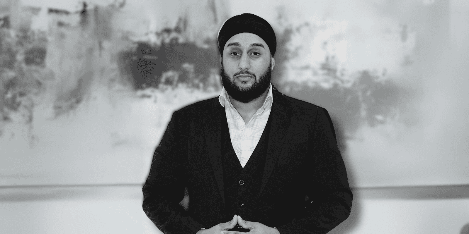 Eknoor Singh Bains, CEO of Limitless Financial, standing confidently in a suit against a blurred abstract background.