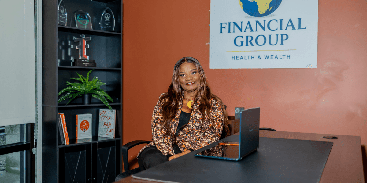 Bilha Wachira seated at a desk beneath the 254 Financial Group Health & Wealth sign.
