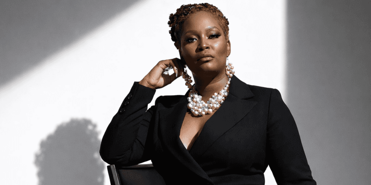 Dr. Shana Gourdine confidently posing in a black suit, exuding strength and empowerment with pearl jewelry.