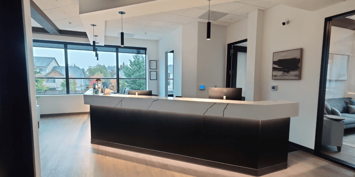 Modern office reception area with large windows and a sleek black-and-white front desk.