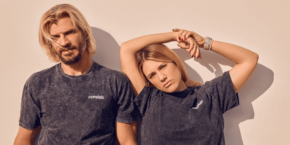 A man and woman in matching CoreLab t-shirts, casually posing in front of a neutral background.