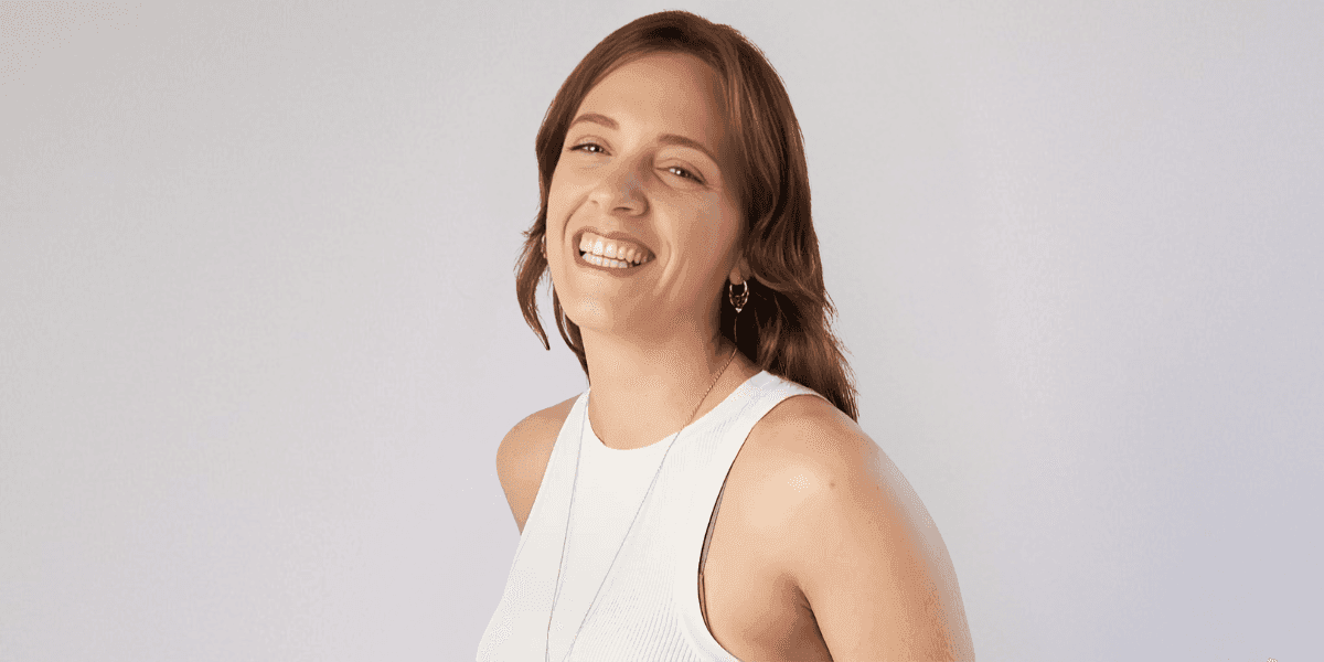 Smiling woman in white top against light background, representing intuitive leadership coach Aude Firmin.