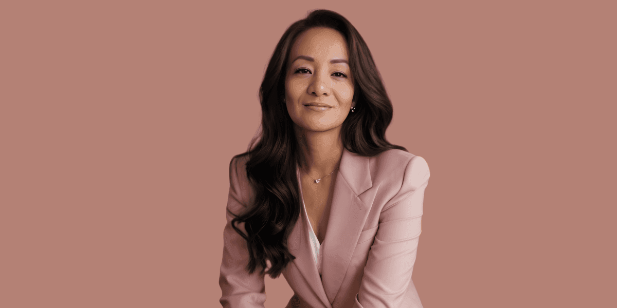 Maria Angeles seated in a pink blazer against a neutral background.