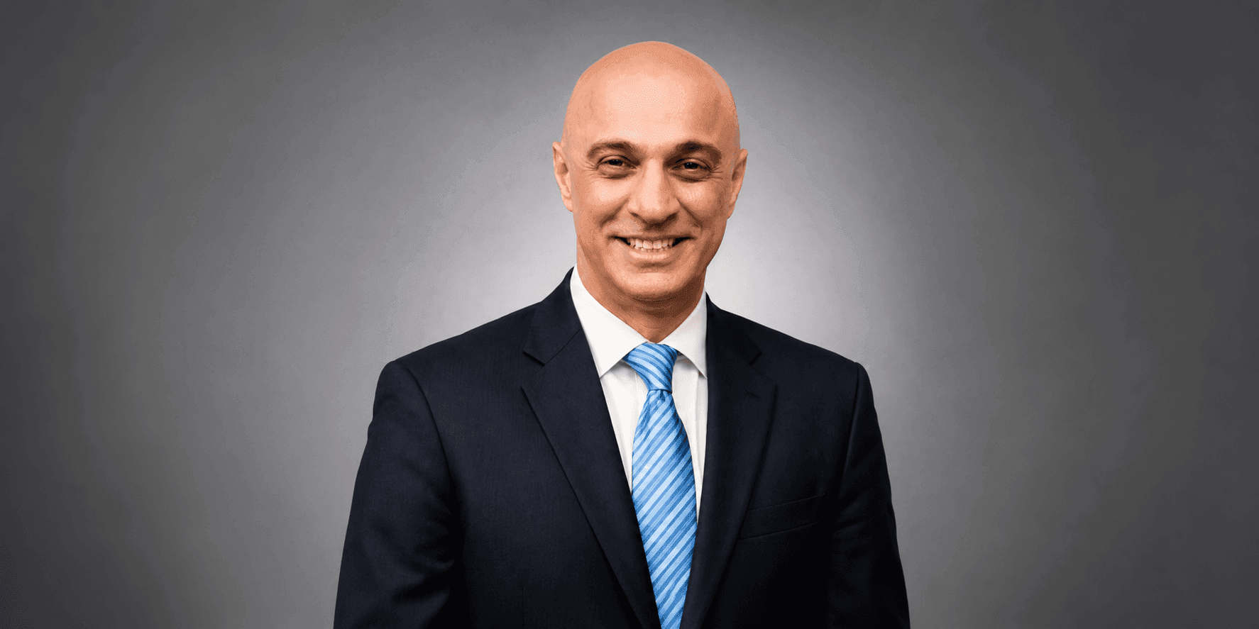 Professional portrait of registered psychotherapist Atul Mehra, smiling in a suit and blue tie.