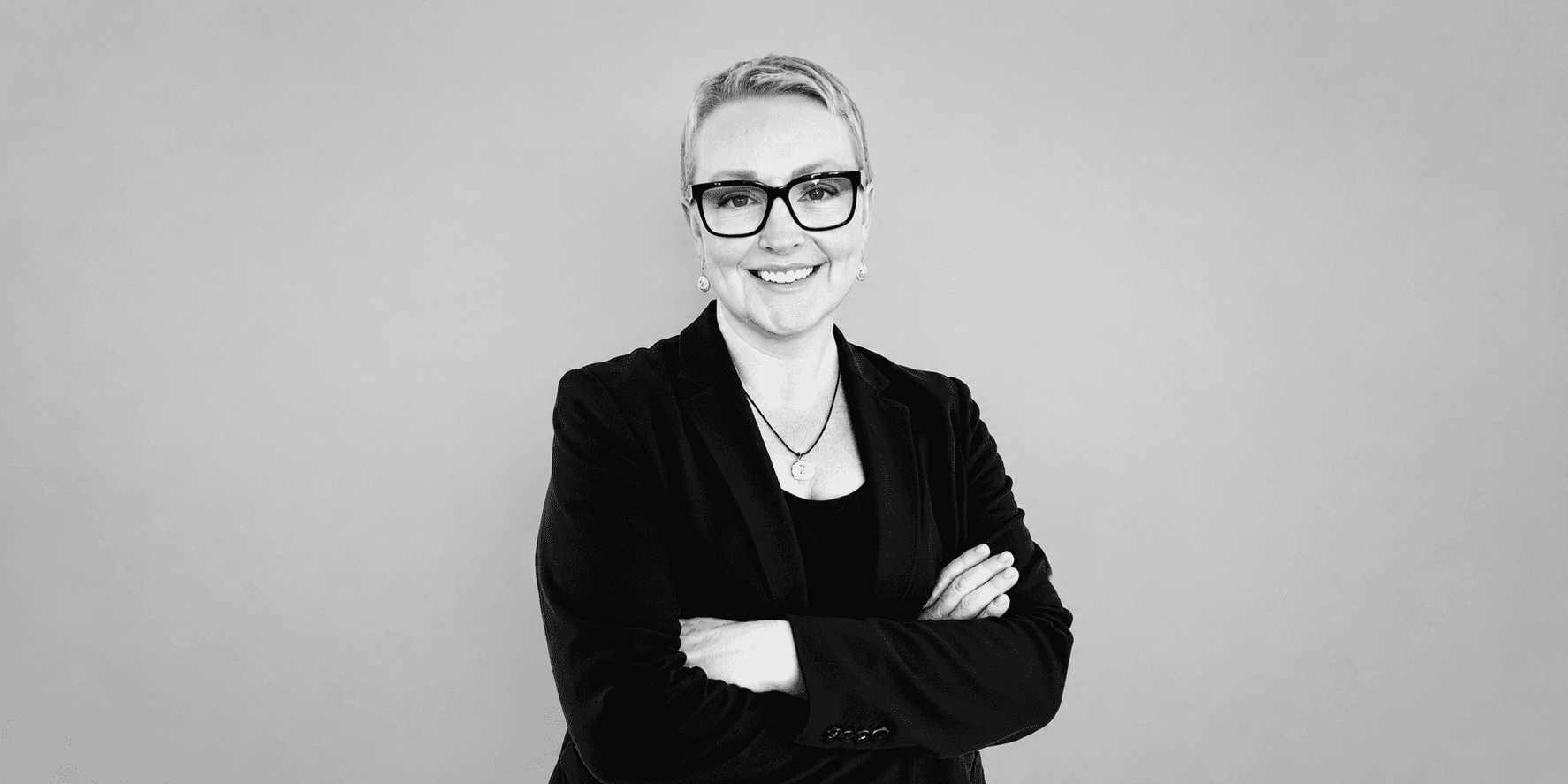 Jeannette Papadakis smiling with folded arms in a professional portrait.