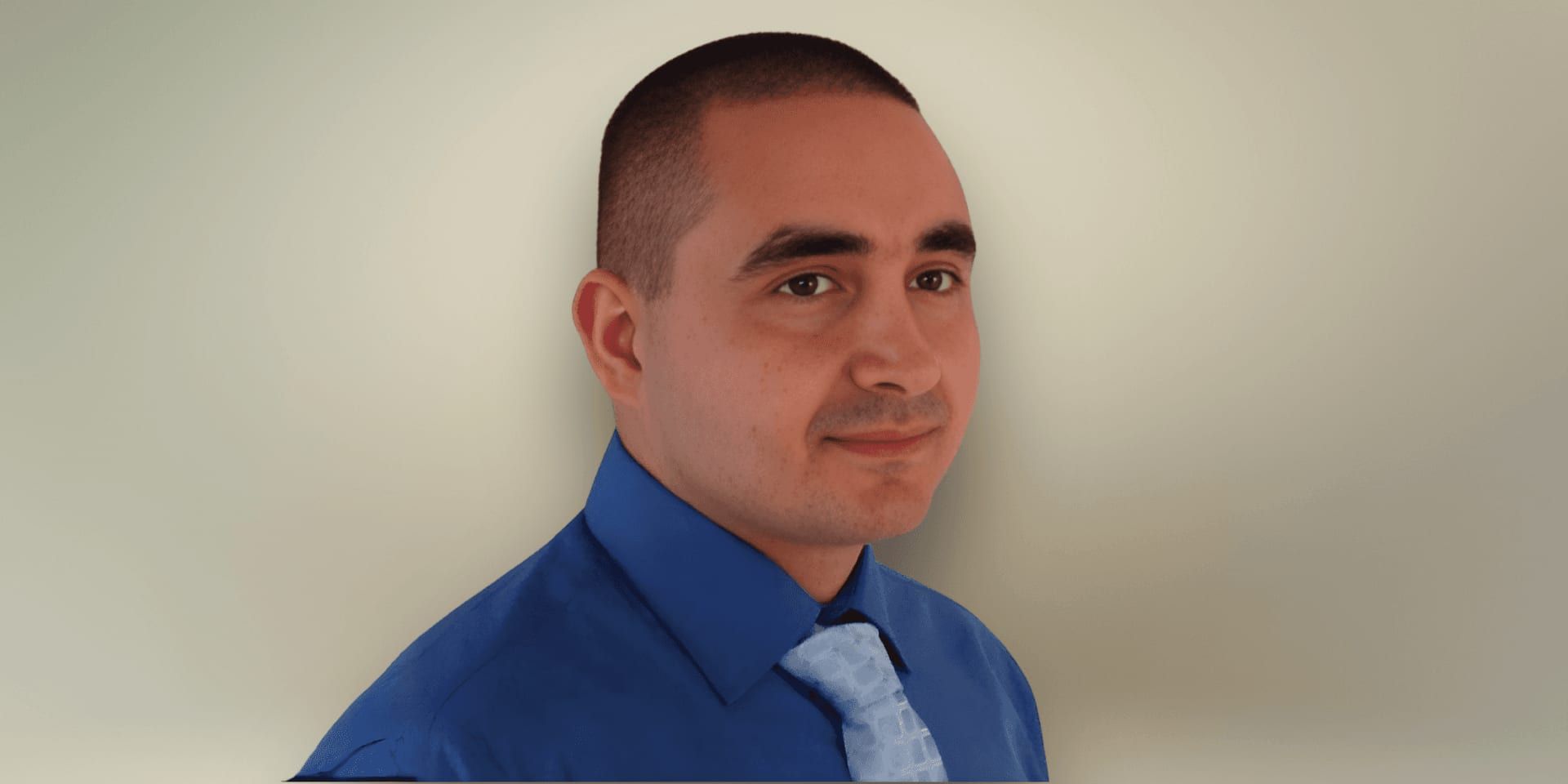 A person with short hair is wearing a blue shirt and light blue tie, posing in profile against a plain light background, conveying a professional tone.