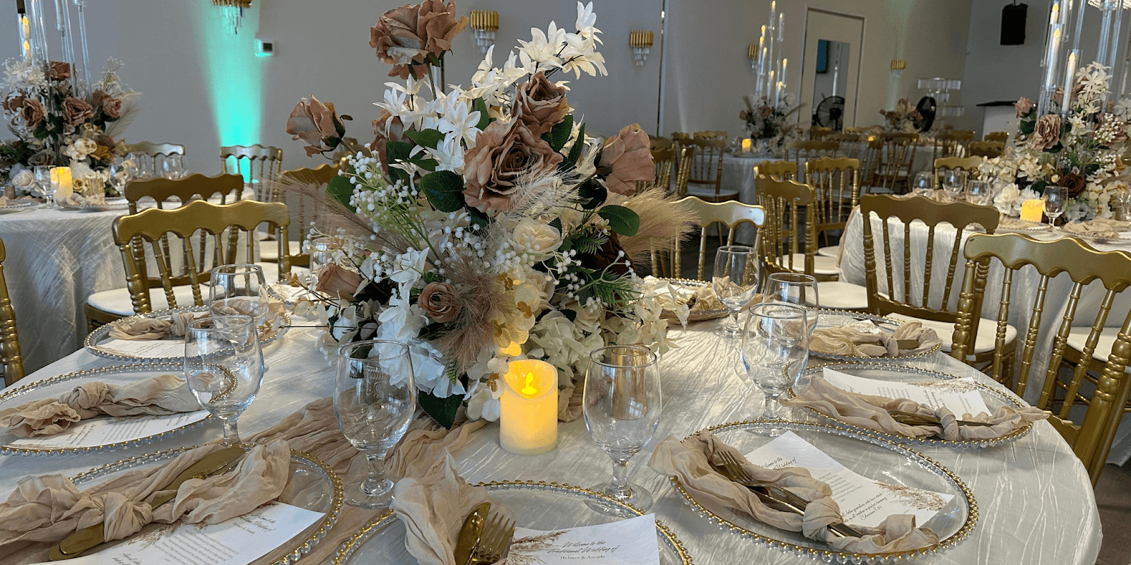 Elegant event setup with gold chairs, floral centerpieces, and candlelit tables at Glitz & Glam Events Center.