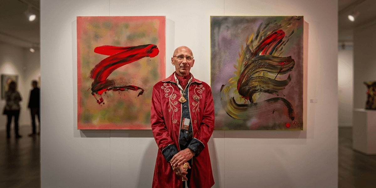 Marc Noël standing between two vibrant abstract quantum paintings at a contemporary art exhibition.