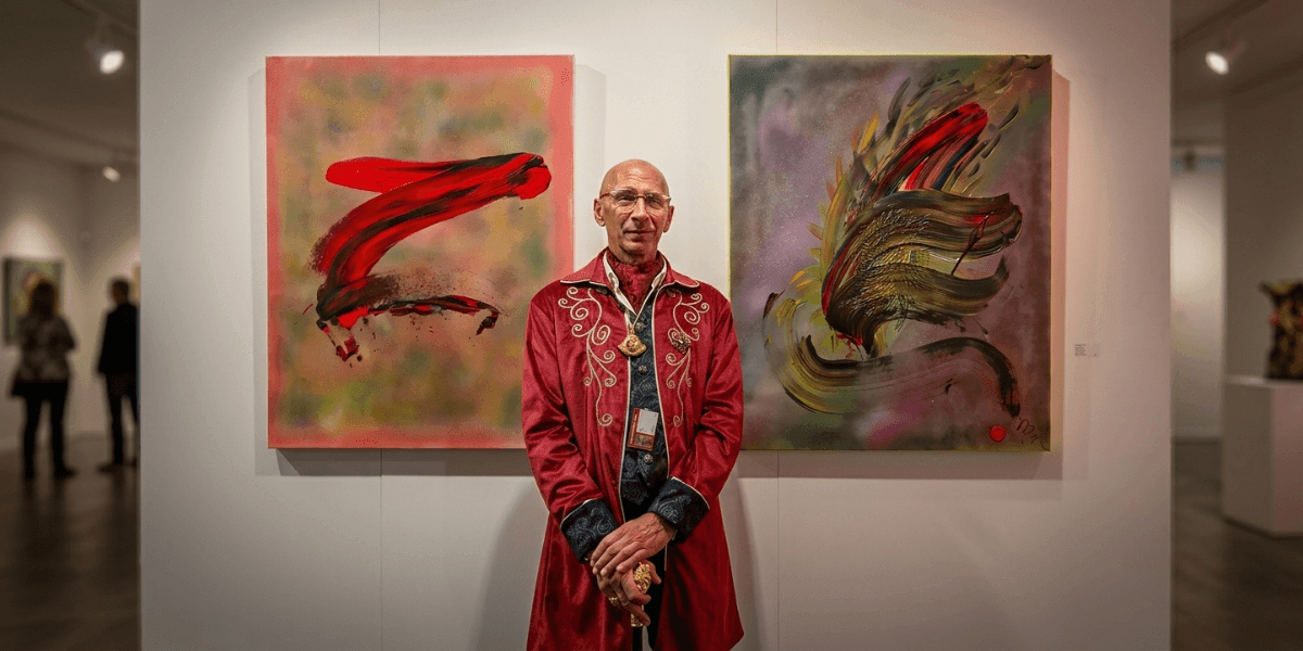 Marc Noël standing between two vibrant abstract quantum paintings at a contemporary art exhibition.