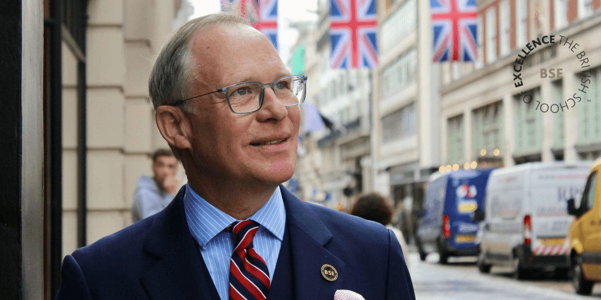 A man in a suit stands confidently on a London street, representing The British School of Excellence™️'s leadership programs.