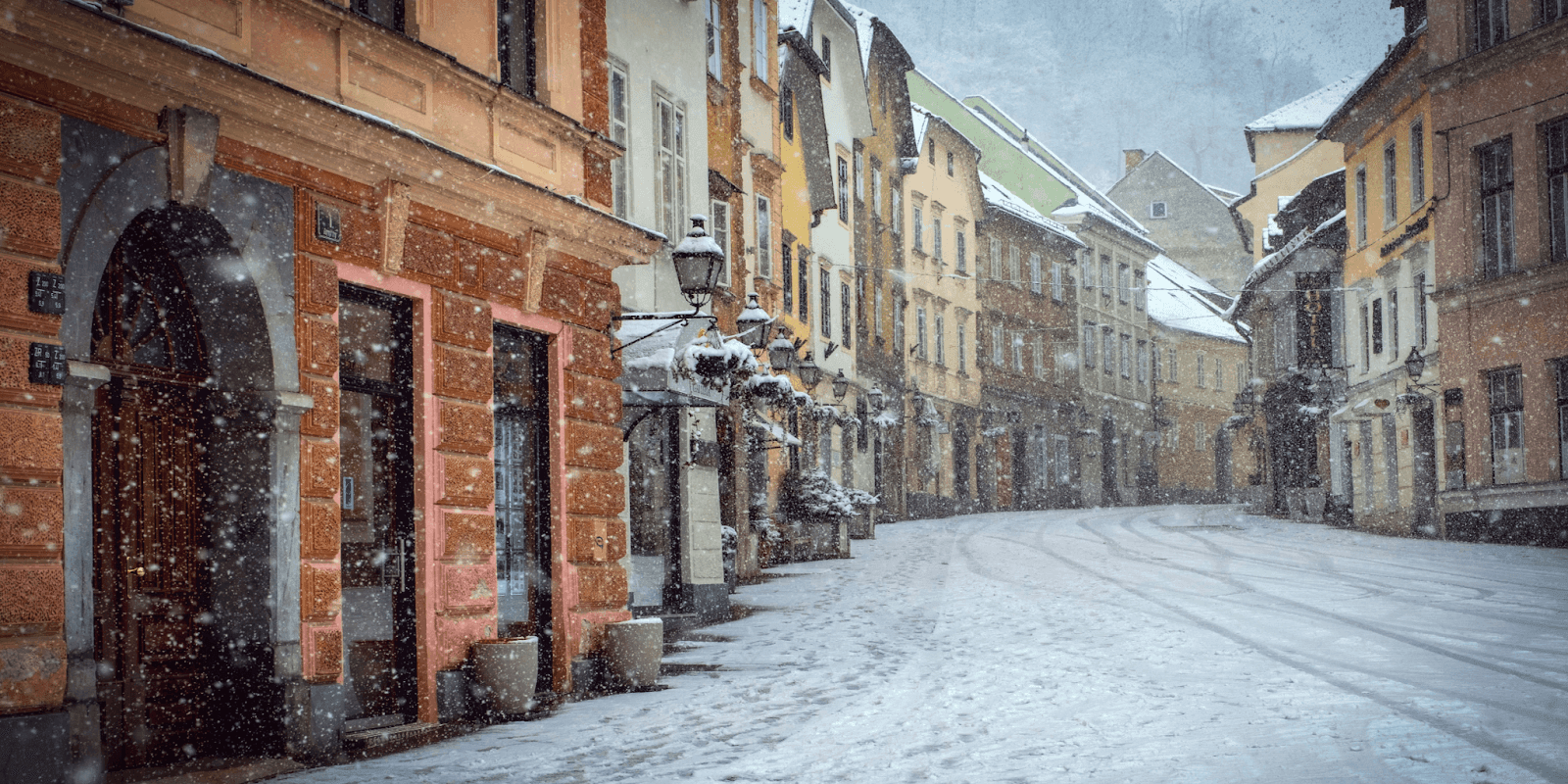 ChatGPT said: Snow-covered European street with colorful historic buildings during a winter snowfall.