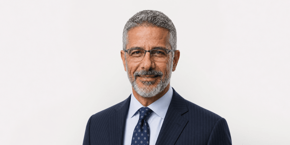 Middle-aged man in a suit with glasses, smiling against a white background
