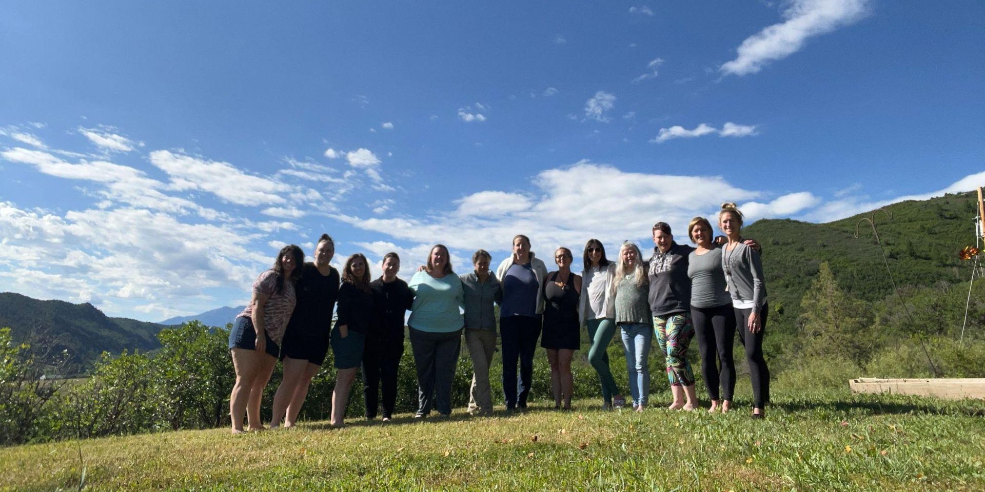 Group of women standing in a line outdoors with a scenic mountain background