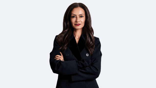 Professional woman in a black coat, arms crossed, with long dark hair
