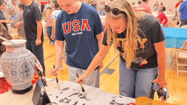 Two women engaged in an activity at a community event, examining artwork together