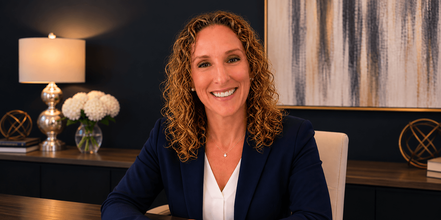 Smiling woman with curly hair in a professional setting, seated at a desk