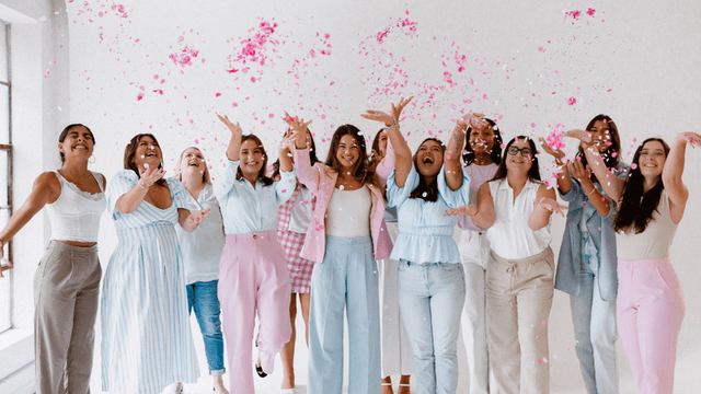 A group of joyful women throwing pink confetti in a bright, cheerful setting