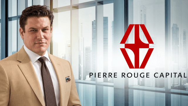 A professionally dressed man poses in an office setting with a capital firm logo