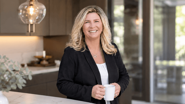 Smiling woman holding a white mug in a modern kitchen setting