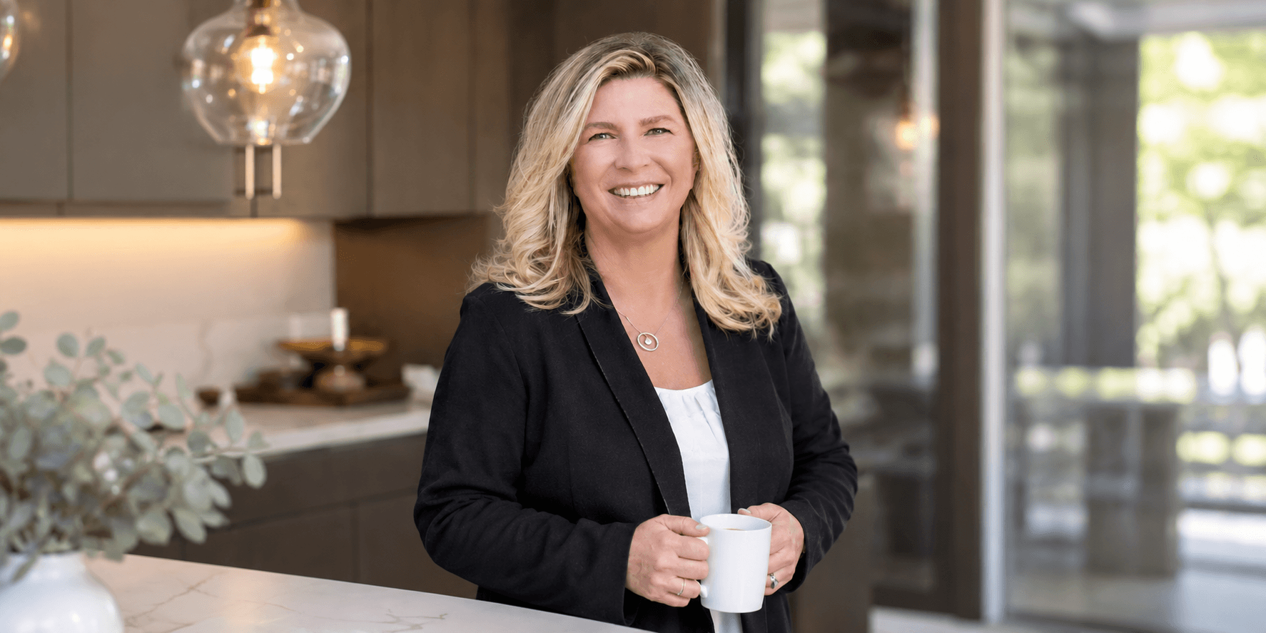 Smiling woman holding a white mug in a modern kitchen setting