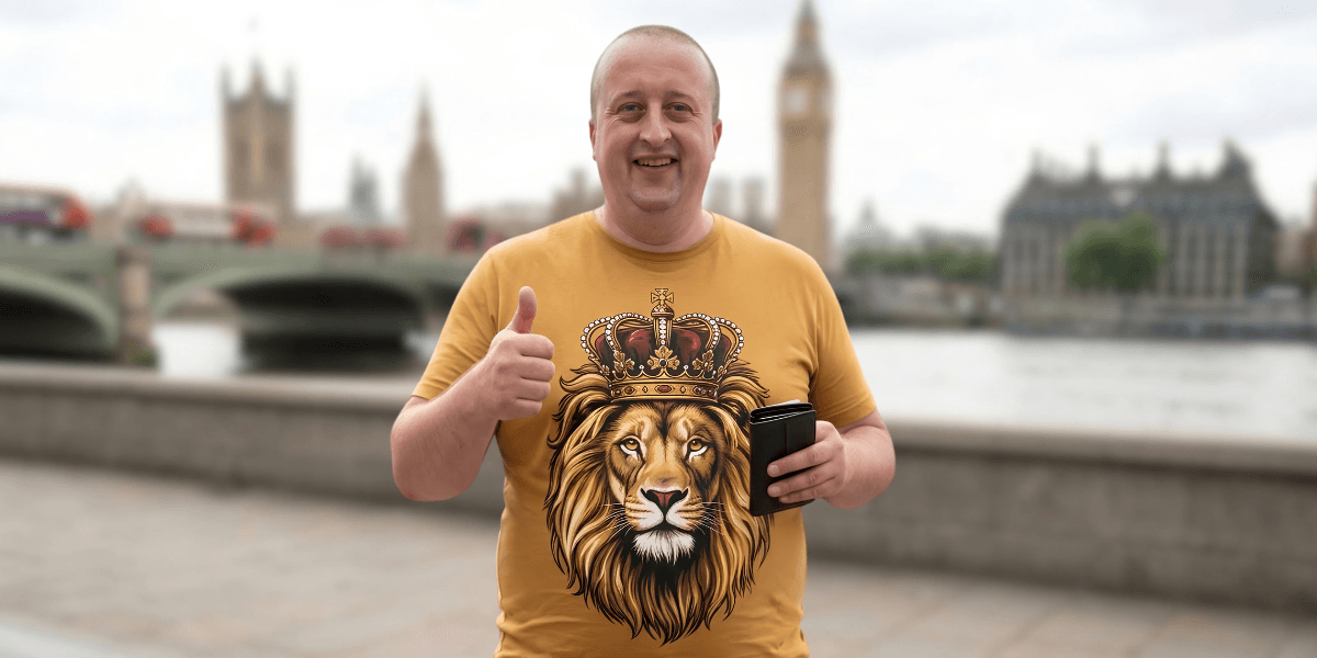 Man in a lion graphic t-shirt gives a thumbs up by a riverfront landmark